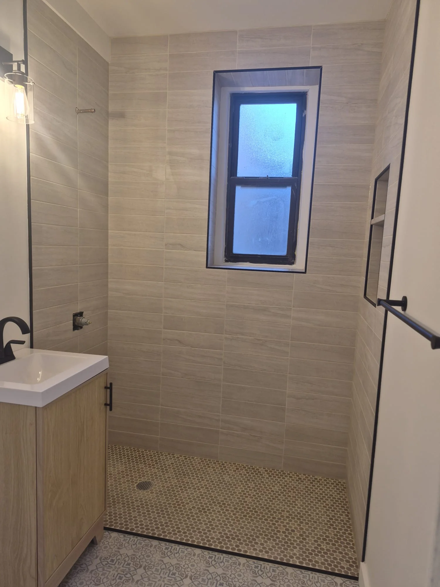 Pre-war master bath remodel in Manhattan — porcelain wall tile, hex pebble shower floor, wood vanity