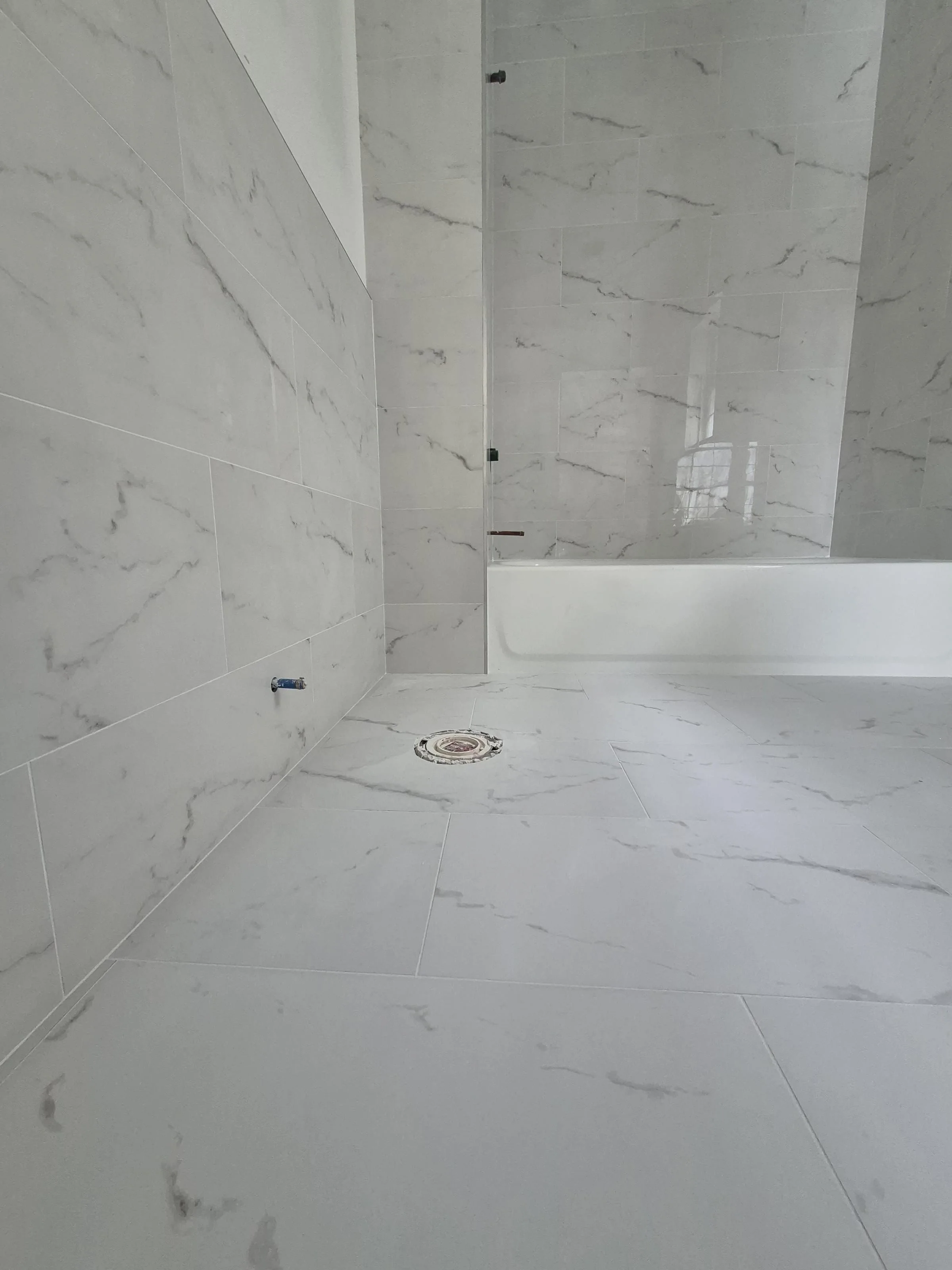 4-floor Brooklyn brownstone whole-home renovation — primary suite with bookmatched marble walls, freestanding tub, and frameless glass walk-in shower