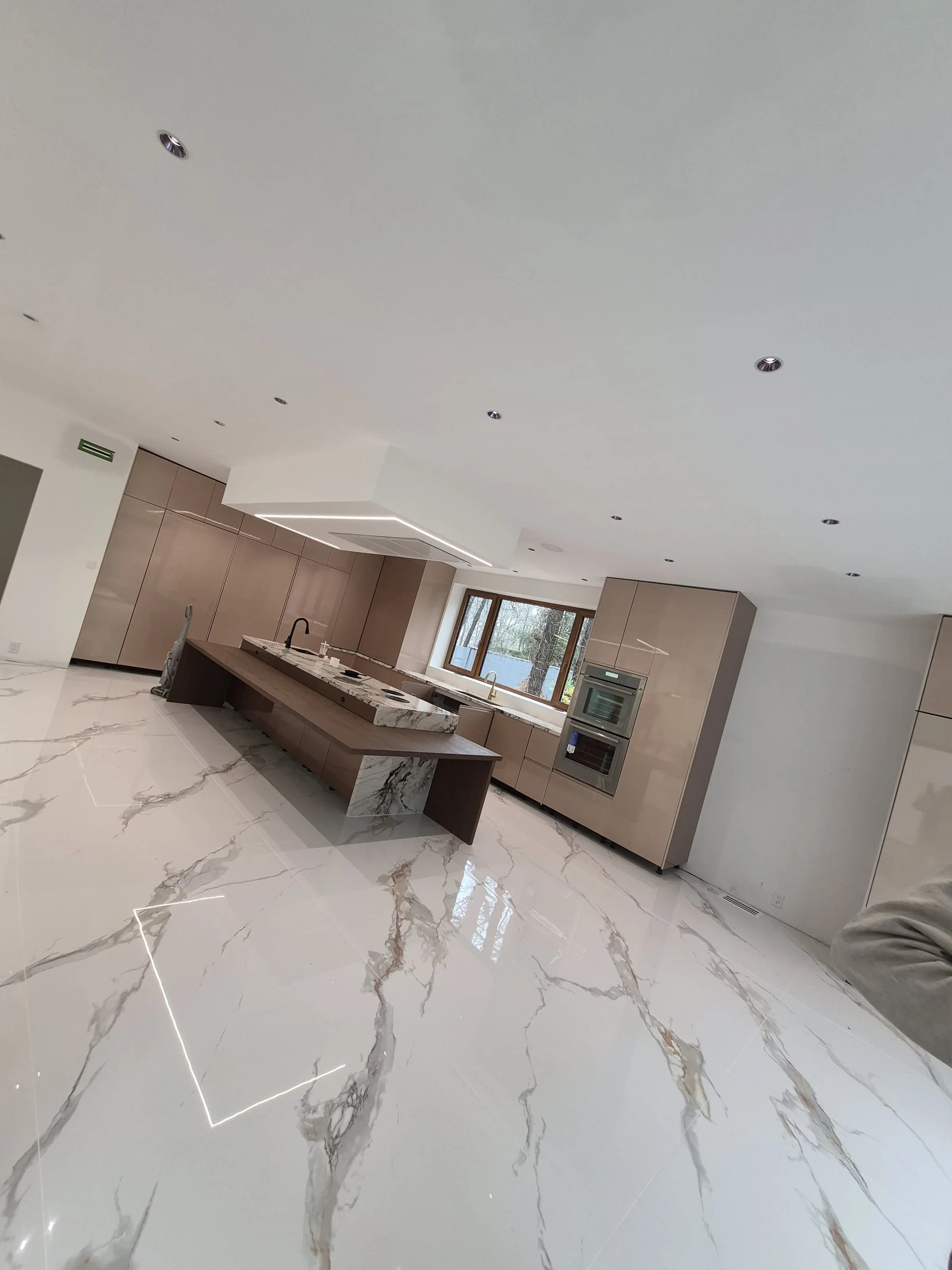 Modern Manhattan condo renovation — handleless cabinetry, marble waterfall island, integrated double-oven wall