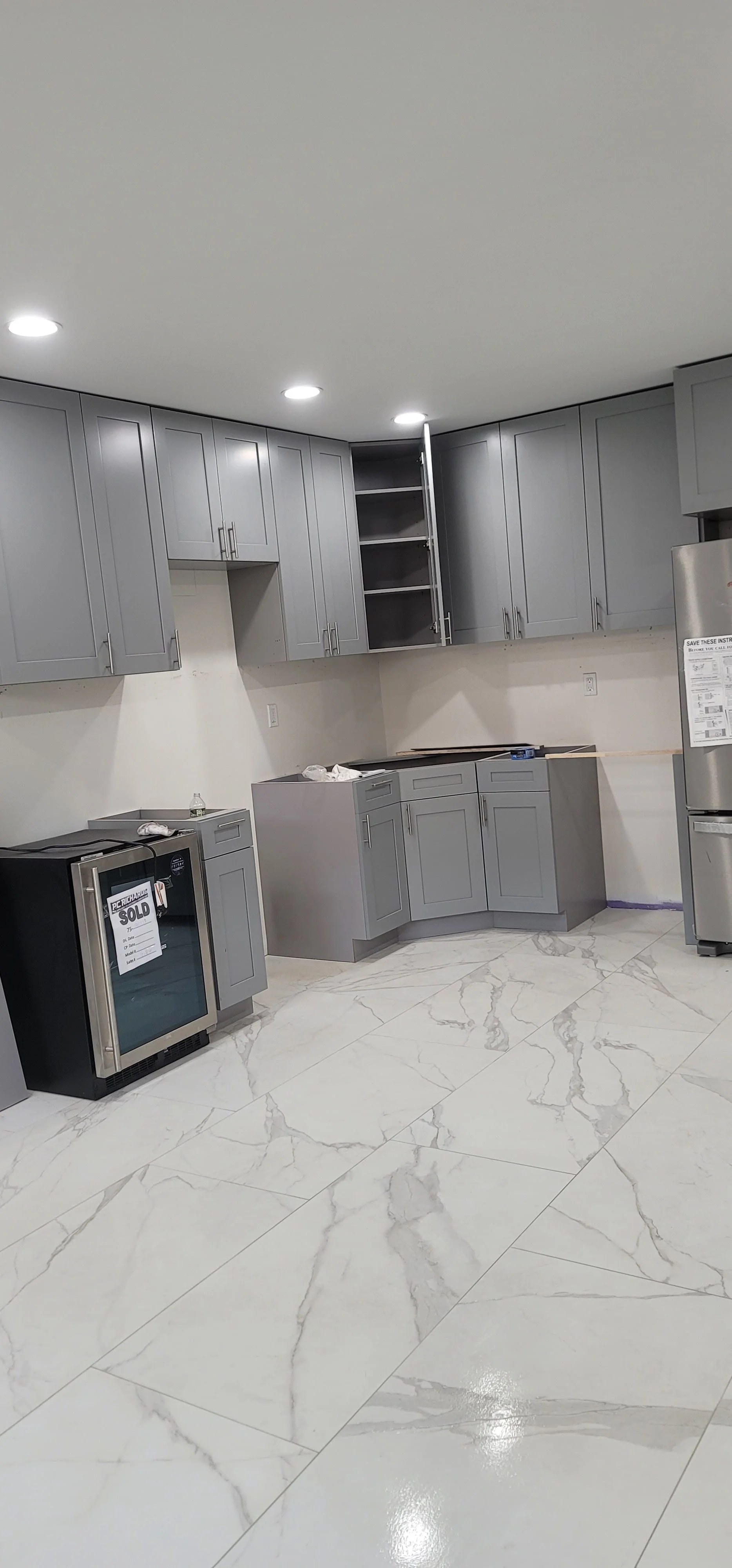 Calacatta gold marble waterfall kitchen island with mitred edges left and right, integrated drainboard at the prep sink, suspended hood